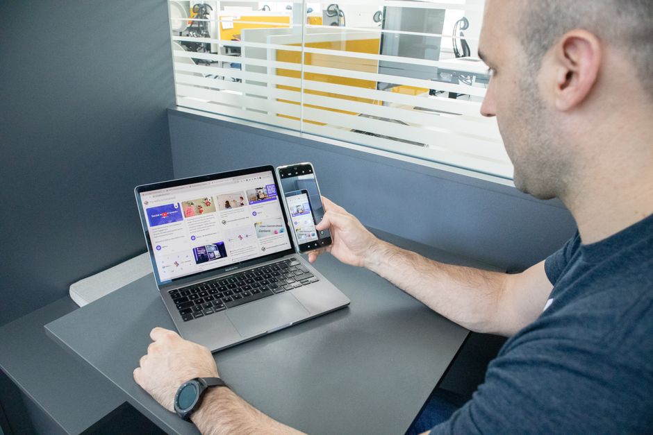 Čovjek koristi prijenosno računalo i pametni telefon u suvremenom uredu